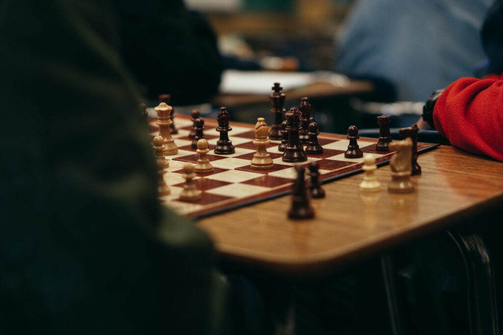 A close-up view of a chess game in progress on a wooden table, showcasing strategic gameplay indoors.