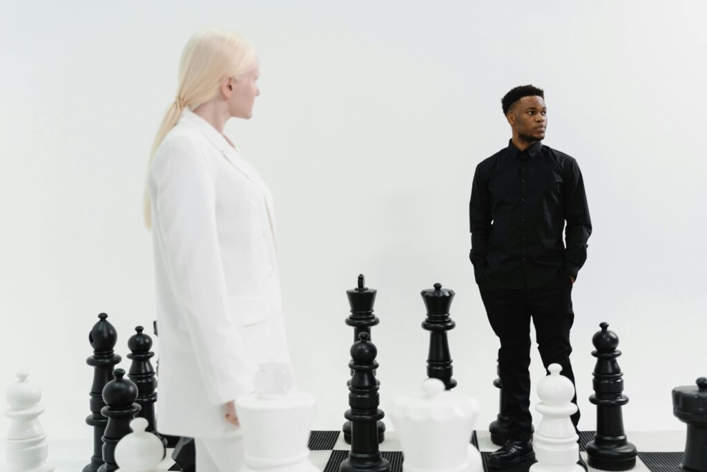 Two individuals strategize in a life-sized chess game, emphasizing competition and strategy.